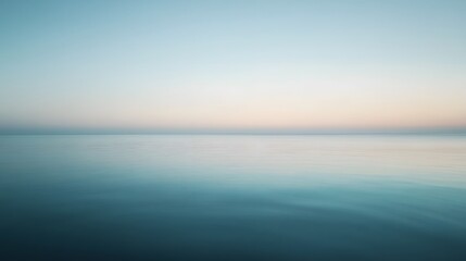 Fototapeta premium A serene vista of tranquil water, showcasing a soft blend of pale blues and pinks, hinting at dawn or dusk, with a calm, hazy horizon.