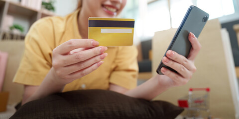 Online Shopping. Young woman using smartphone and credit card for e-commerce purchase.