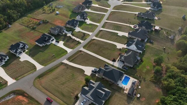 Red car arriving luxury single family house in suburb of american town. Sunny day in quiet and noble district. Aerial flyover shot. Swimming pool in backyard. New developed district in Virgina State.