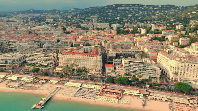 Drone footage of scenic cityscape with Carlton Cannes hotel in front during daytime.