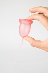 Hand holding pink reusable silicone menstrual cup