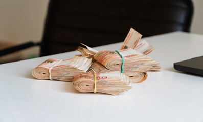 Russian national currency banknotes in large roll stack on the table. Stacks of 5,000 rubles on the table. Five thousand Russian rubles banknotes on wooden table. Stack of much bills 5000 ruble notes.