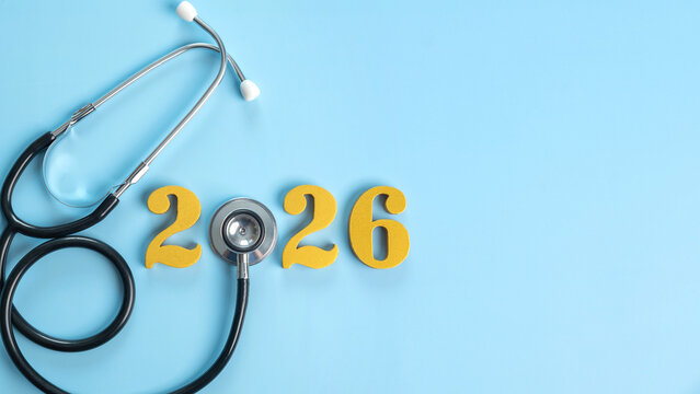 Stethoscope with golden numbers 2026 on a light blue background represents health planning, medical insurance coverage, wellness goals, family care, and budgeting for the new year with copy space.