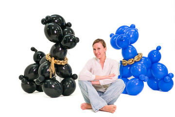 A woman sits in front of two poodles, one of which is chained
