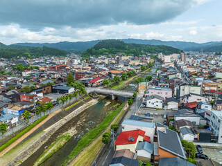 Aerial view of the serene Miyagawa River meandering through the heart of the city, with traditional buildings nestled amidst lush greenery, Takayama, Gifu, Japan.