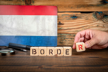 Wooden blocks spelling BORDER in front of Netherlands flag. Concept of geography, travel, immigration, European countries and international relations
