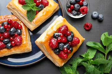 Tasty puff pastries with berries and mint on grey wooden table, flat lay