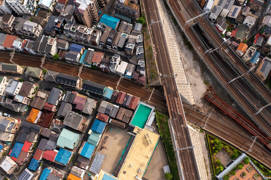 Aerial view of dense urban landscape with colorful rooftops contrasting against the parallel railway tracks, creating a dynamic interplay of order and chaos, Tokyo, Tokyo, Japan.