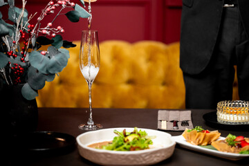 Elegant dinner table with champagne pouring, festive food, and stylish decor. Celebratory atmosphere with gourmet dishes and holiday accents in upscale restaurant setting.