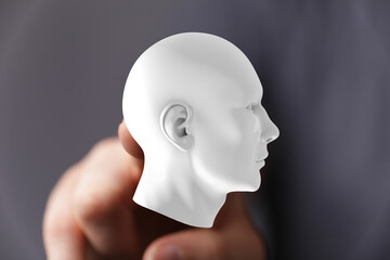 Stock photo of a hand holding a white head model.  Perfect for AI, intellect, and thought concepts.