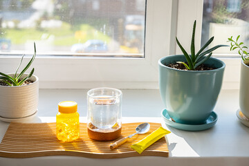 Glass of water with vitamin supplement and spoon on wooden tray. Daily medicine intake.