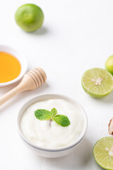 Yogurt, lime and honey on white background