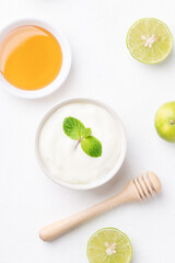 Top view of yogurt, lime and honey on white background