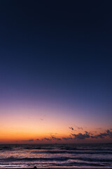 Before the sunrise. Bright multi colored sky on the background and dark blue sea in the foreground. Heavy clouds just above the horizon. 