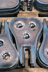 Stack of precision-cut steel machine parts with drilled holes, industrial metal components for engineering and manufacturing