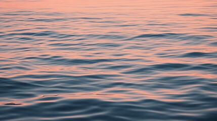Gentle water ripples, reflecting the soft, peachy hues of a serene sunset, create a captivating texture.