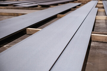 Stacked steel sheets in warehouse, industrial metal plates stored on wooden supports, construction material manufacturing and supply background