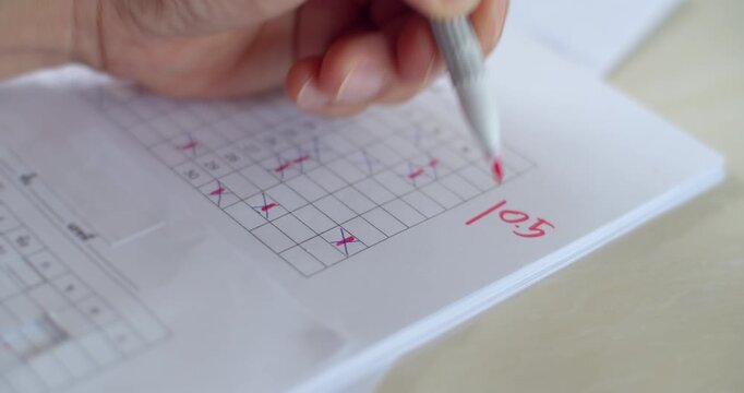 Writing student scores with a red pen after grading the final exam.