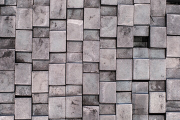 Stacked industrial metal blocks with varying textures, abstract pattern of square steel billets in warehouse or manufacturing facility