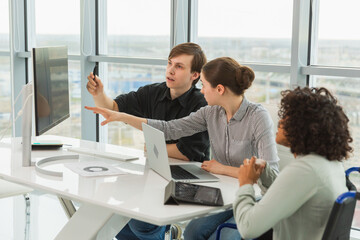 Obraz premium Teamwork brainstorm. Diverse multiracial colleagues woman in chair for people with disability working together. Group of people sitting in creative office discussing business. Young professional team