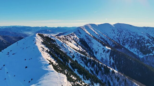 Aerial drone view of the Mala Fatra mountains with snow-covered peaks and hikers along the ridge under clear blue skies, highlighting the pristine beauty of this range. Location: Mala Fatra, Slovakia