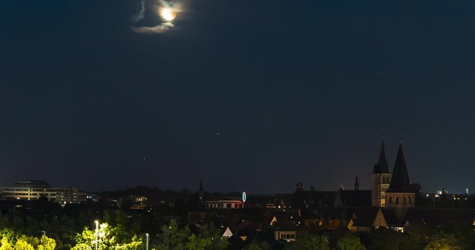 Red moon rises above Mechelen cityscape, time lapse view