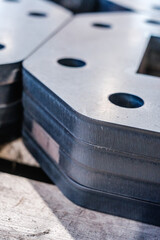 Stacked metal components with precision-cut holes, industrial steel fabrication detail, close-up of machined parts in workshop setting