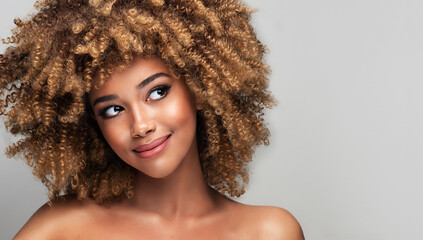 Beauty portrait of african american woman with clean healthy skin on beige background. Smiling...