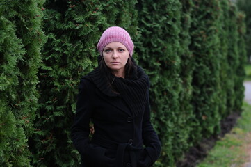 girl in a black coat and hat against a green wall