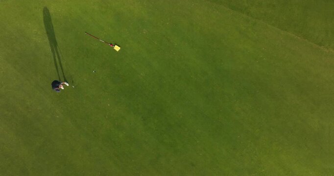 Aerial view of golfer putting ball into hole and replacing flagstick