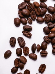 Scattered roasted coffee beans on white background closeup