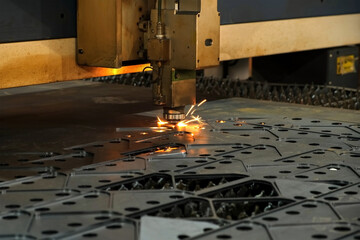 Automated industrial laser plasma machine is cutting metal sheet into pieces. Generates flying sparks as beam slices through, transforming material into metal polygons. Production of metal details.