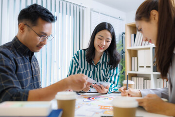 Obraz premium Three people are sitting at a table with a whiteboard behind them. One of the people is holding a pen and looking at a diagram on the board. Scene is focused and serious 