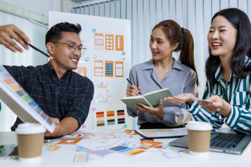 Obraz premium Three people are sitting at a table with a whiteboard behind them. One of the people is holding a pen and looking at a diagram on the board. Scene is focused and serious 
