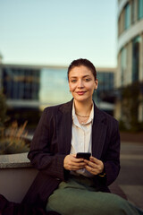 Confident Business Woman in Pinstripe Blazer Using Smartphone Outdoors at Modern Office Complex