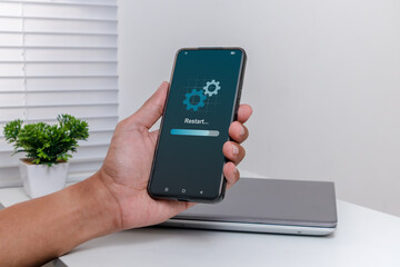 Man holding a smartphone with operating system being restarted or rebooted