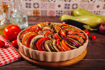 Homemade ratatouille with slices of zucchini, eggplant, tomato, red onion and herbs brushed with olive oil. Vegetarian meal.