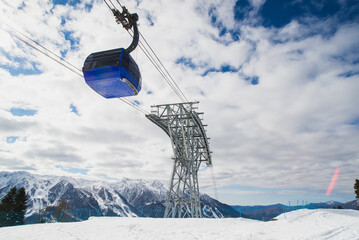Gondola, cable car and ski lift with mountain, tree, blue sky on a sunny day at resort Krasnaya Polyana.