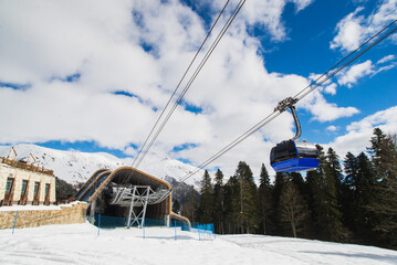 Gondola, cable car and ski lift with mountain, tree, blue sky on a sunny day at resort Krasnaya Polyana.