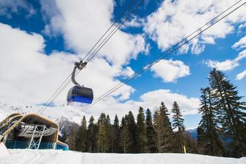 Gondola, cable car and ski lift with mountain, tree, blue sky on a sunny day at resort Krasnaya Polyana.