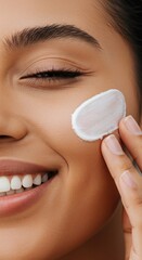 Close-Up of a Smiling Woman Applying Moisturizing Cream to Her Cheek