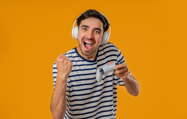 Excited Gamer Man Playing Online Video Game On Console With Gamepad On Yellow