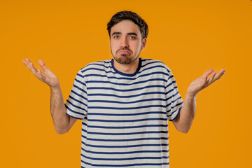 Young man shrugs shoulders showing uncertainty, confusion, dilemma, hesitation