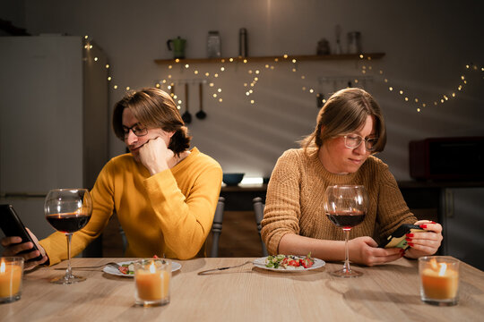 Young couple in love sitting back to back focused on their smartphones ignoring each other