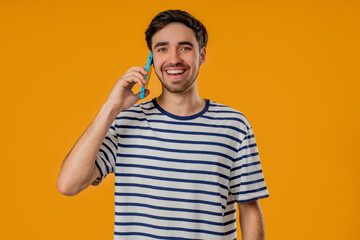 Smiling Positive Man Talking By Phone, Smiling. Young Guy On yellow Background.