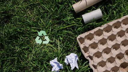 concept of ecology and recycling waste - paper, glass, plastic, cardboard, green grass in the background. Recycling eco symbol, reuse, conscious consumption, caring for nature flat lay, top view