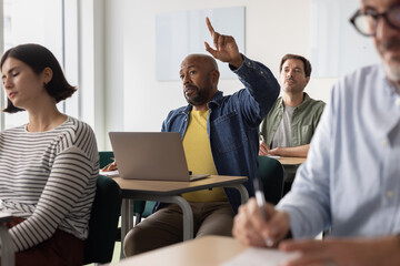 Engaged adult student raising his hand in class