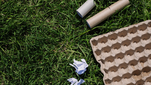 concept of ecology and recycling waste - paper, glass, plastic, cardboard, green grass in the background. Recycling eco symbol, reuse, conscious consumption, caring for nature flat lay, top view