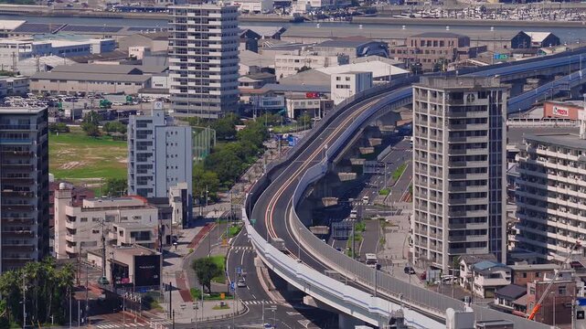 A slow pan across Hiroshima city, Japan, showing modern buildings, organized streets, lush greenery, and distant mountains in a dynamic layout.