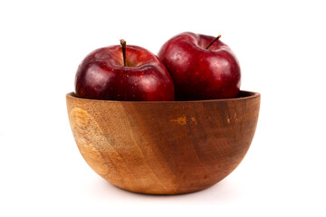 Rustic wood bowl holds shiny delicious apples presenting simple, healthy fruit composition.